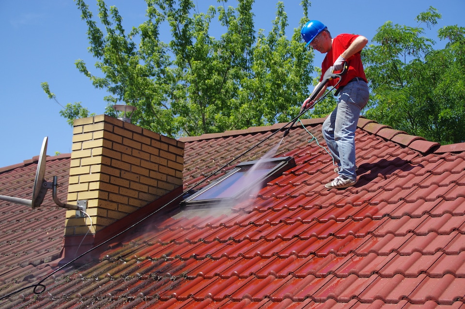 roofer washing a red clay tile roof