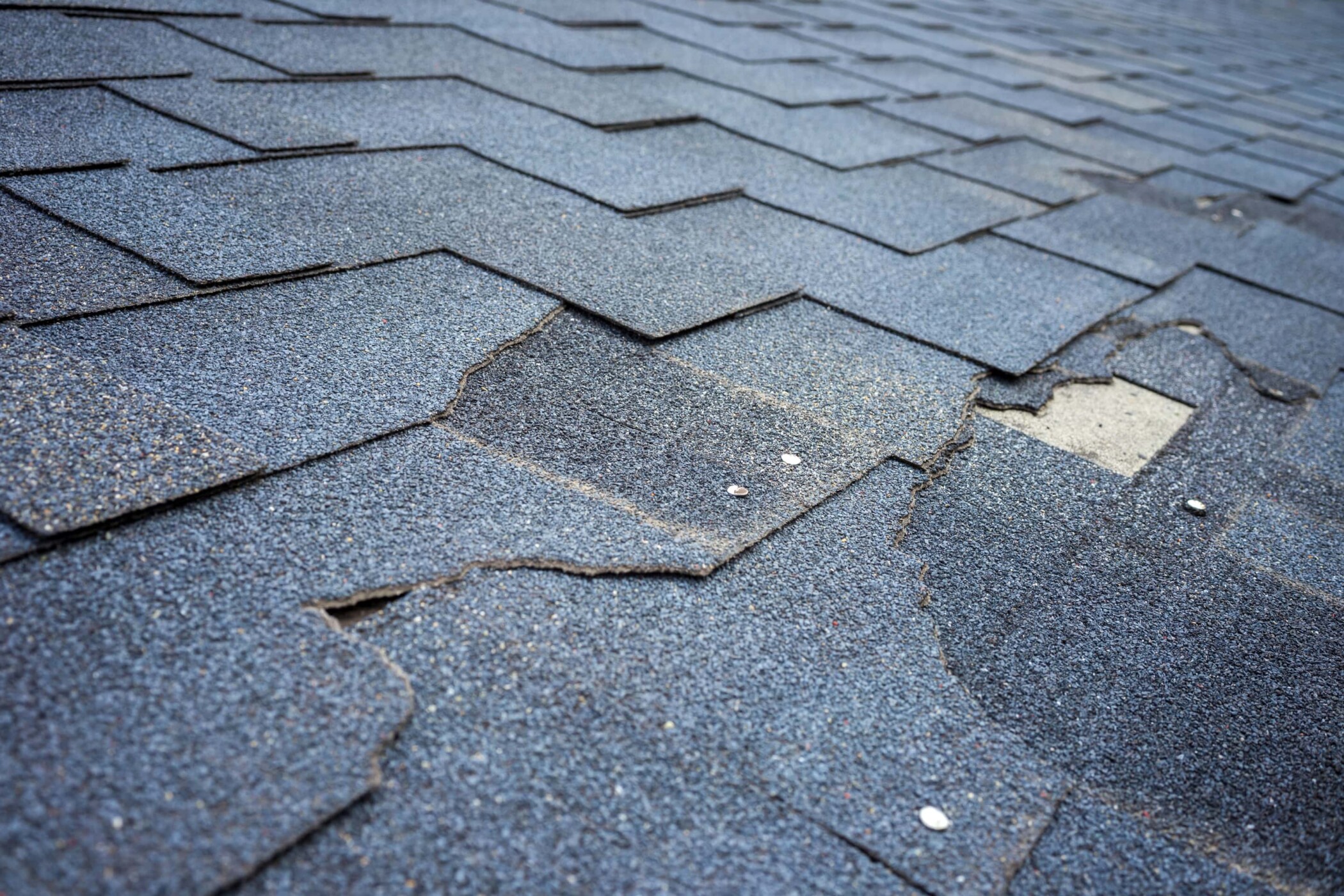 broken asphalt shingles creating a roof leak