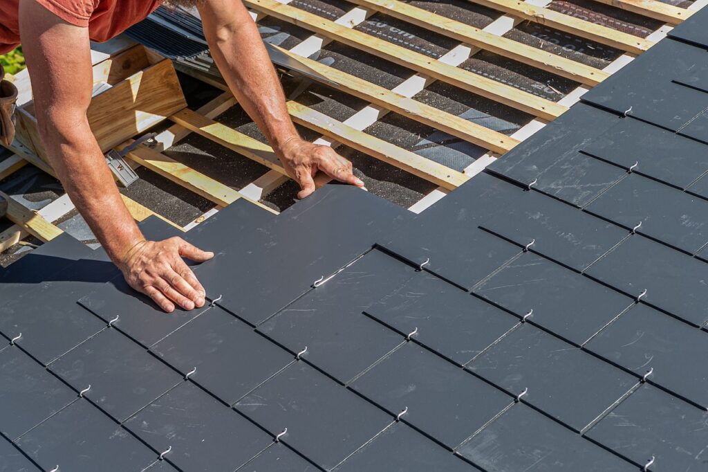 worker putting slate tiles on a roof