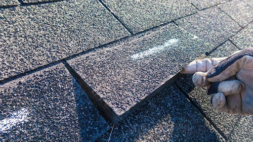 how to shingle a roof-close up of a hand peeling up a shingle from a roof