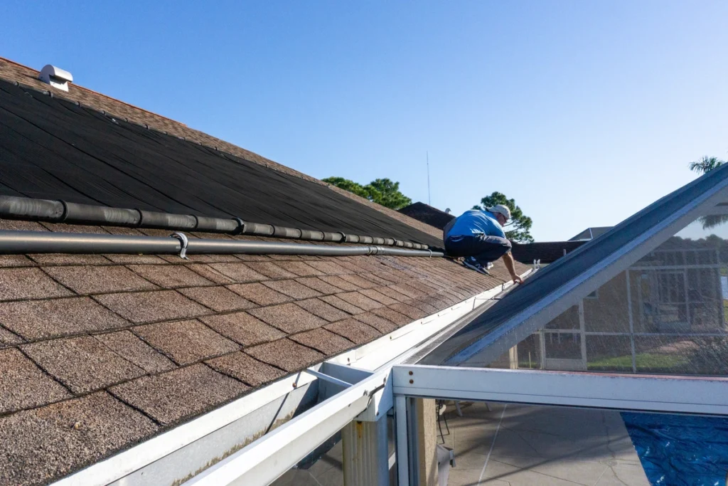 roof tech standing on a roof inspecting gutters