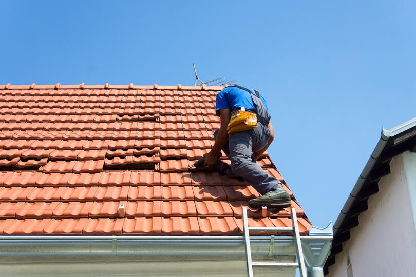 tile roof repair-roof tech standing on a roof repairing tile shingles