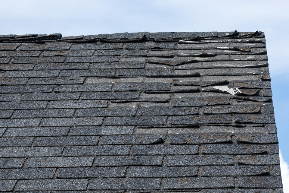 curling shingles-corner of roof with curling and damaged roof shingles